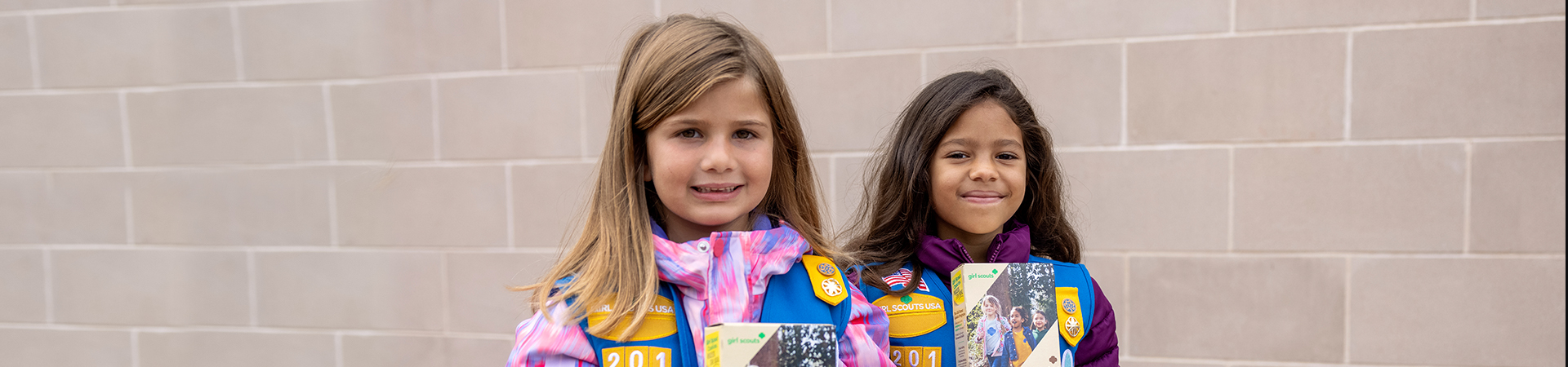  two girls holding cookie boxes 