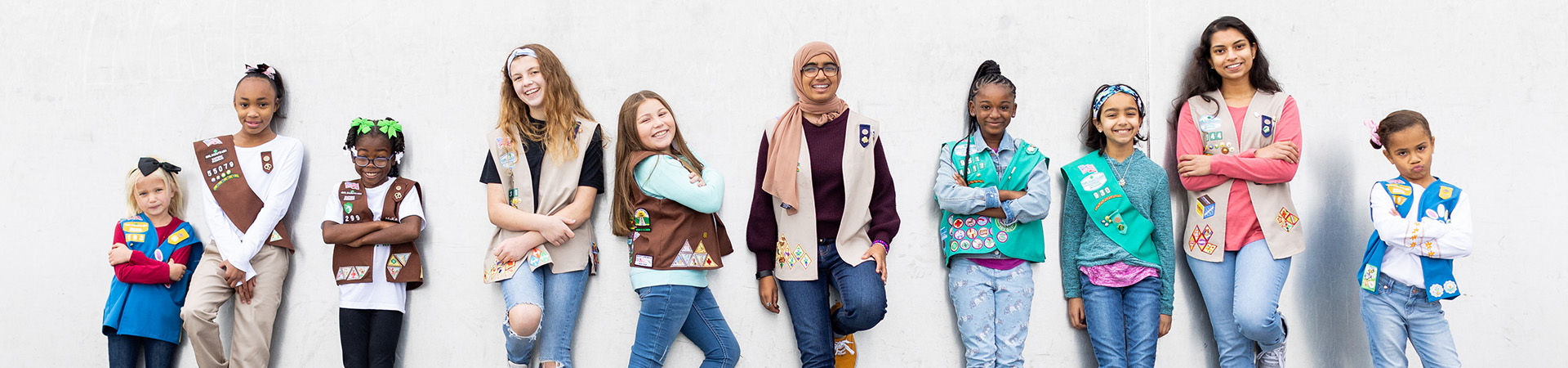  girl scouts standing against wall 