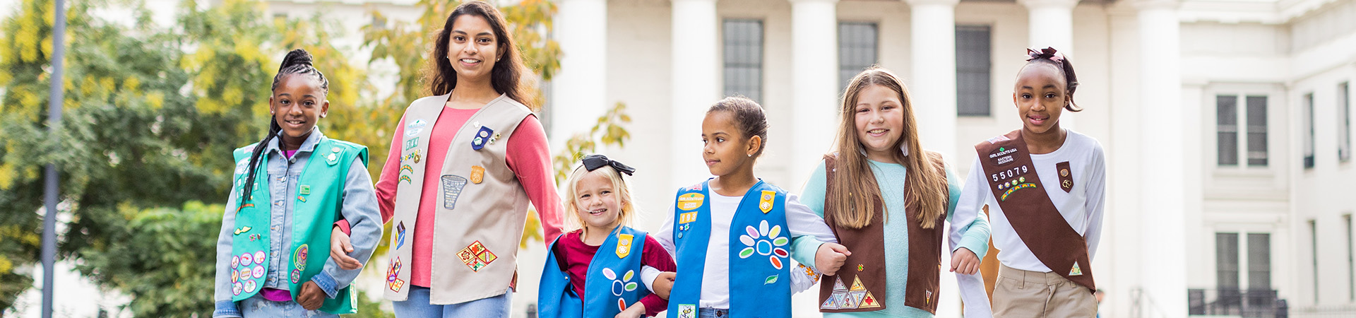  girl scouts in front of building smiling 
