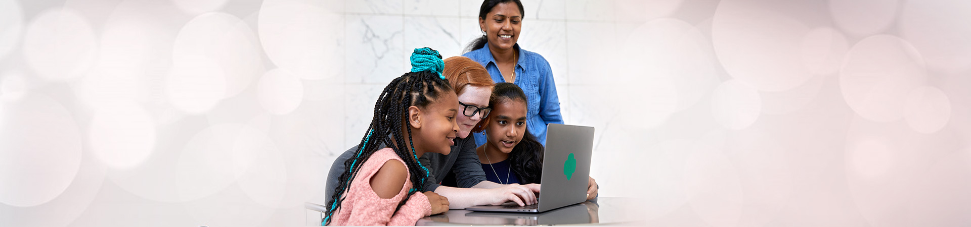  girls and volunteer using laptop 