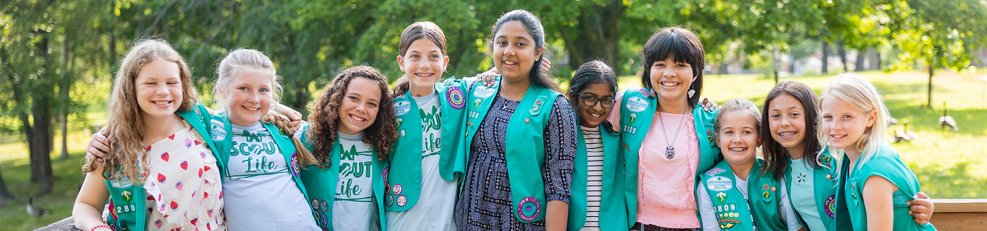  girl scouts with their arms wrapped around one another and smiling at the camera 